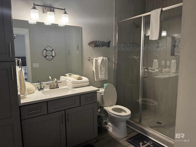 full bath with toilet, a stall shower, wood finished floors, and vanity