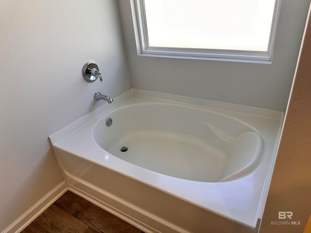 bathroom with hardwood / wood-style floors and a tub to relax in