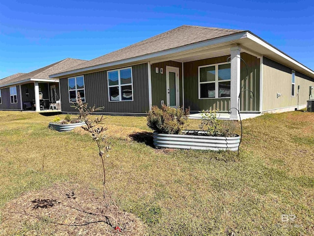 rear view of house featuring central air condition unit and a lawn