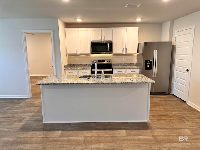 kitchen with light hardwood / wood-style floors, white cabinetry, stainless steel appliances, and a kitchen island with sink