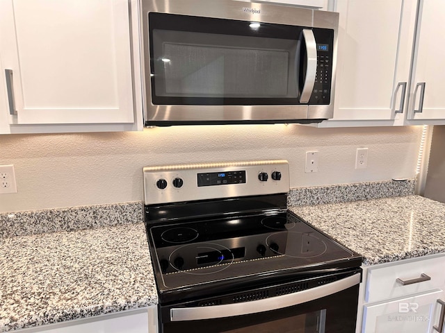 kitchen featuring light stone countertops, appliances with stainless steel finishes, and white cabinetry