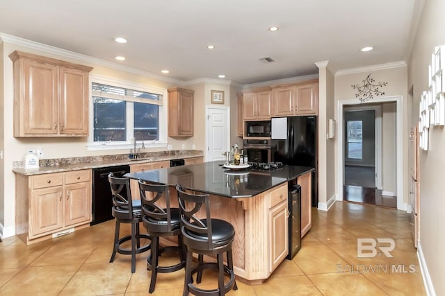 kitchen featuring a center island, light brown cabinets, a breakfast bar, and black appliances