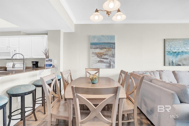 dining room with hardwood / wood-style floors, sink, and ornamental molding