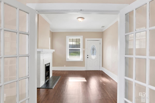 foyer entrance featuring baseboards, crown molding, wood finished floors, and a fireplace