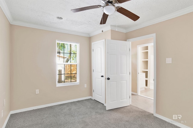 unfurnished bedroom featuring carpet, a ceiling fan, ornamental molding, baseboards, and a textured ceiling
