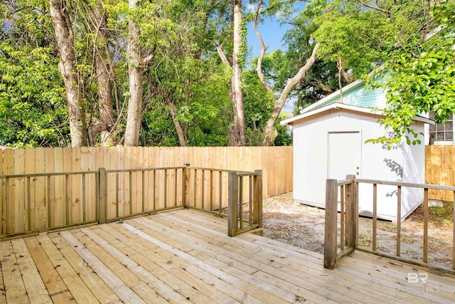 wooden terrace featuring a fenced backyard, an outbuilding, and a storage shed