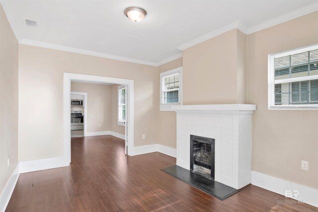 unfurnished living room featuring crown molding, wood finished floors, a fireplace, baseboards, and visible vents