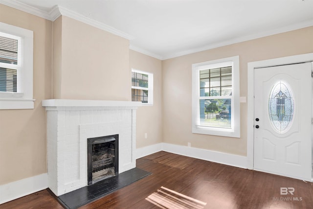 entrance foyer with baseboards, ornamental molding, a brick fireplace, and dark wood-style floors