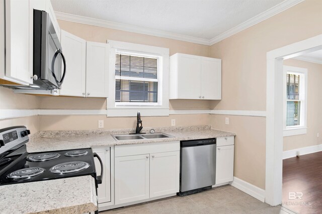 kitchen featuring plenty of natural light, a sink, crown molding, appliances with stainless steel finishes, and white cabinetry