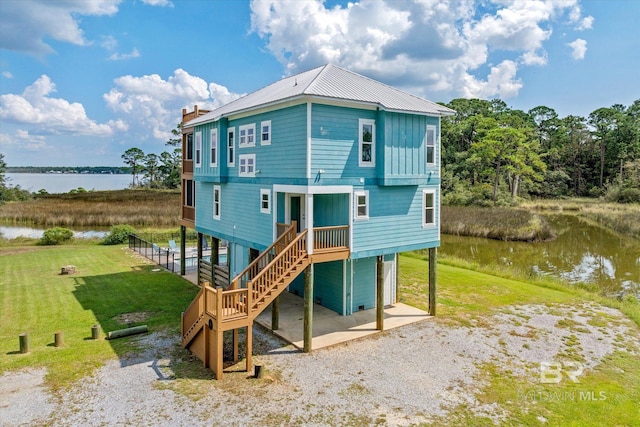 back of property with a water view and a yard