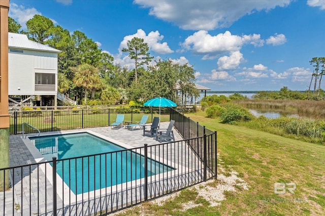 view of swimming pool featuring a patio, a water view, and a yard