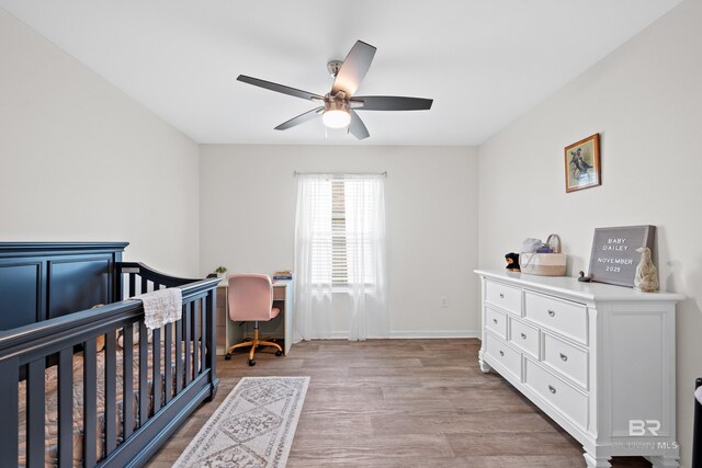 14705 Forsythia Loop, Silverhill, AL 36576 - bedroom with light wood finished floors, a crib, a ceiling fan, and a desk