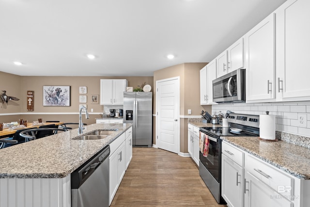 14705 Forsythia Loop, Silverhill, AL 36576 - kitchen with appliances with stainless steel finishes, white cabinetry, an island with sink, recessed lighting, and tasteful backsplash