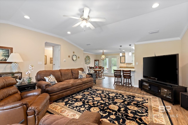 living room with visible vents, lofted ceiling, light wood-style floors, and ornamental molding