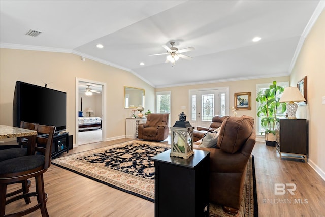 living room featuring vaulted ceiling, light wood-style floors, baseboards, and ornamental molding