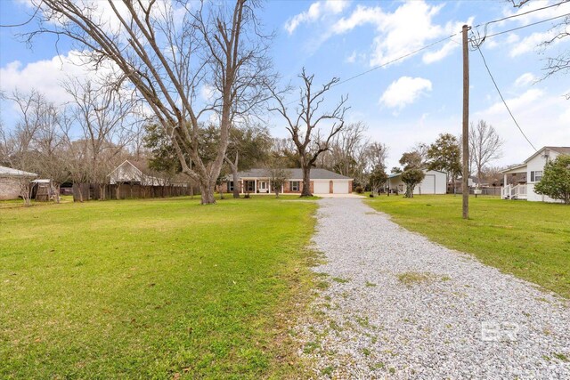 ranch-style house with driveway, an attached garage, a front lawn, and fence