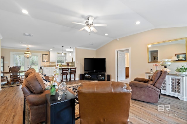 living area with visible vents, light wood-style flooring, crown molding, and lofted ceiling