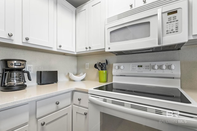 kitchen featuring white appliances, white cabinetry, backsplash, and light stone countertops