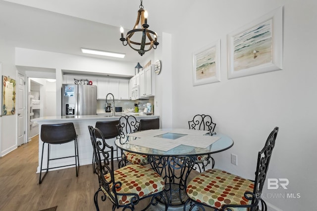 dining area featuring light wood-type flooring, baseboards, and an inviting chandelier