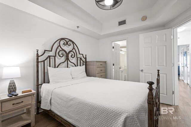 bedroom featuring visible vents, wood finished floors, and ensuite bathroom