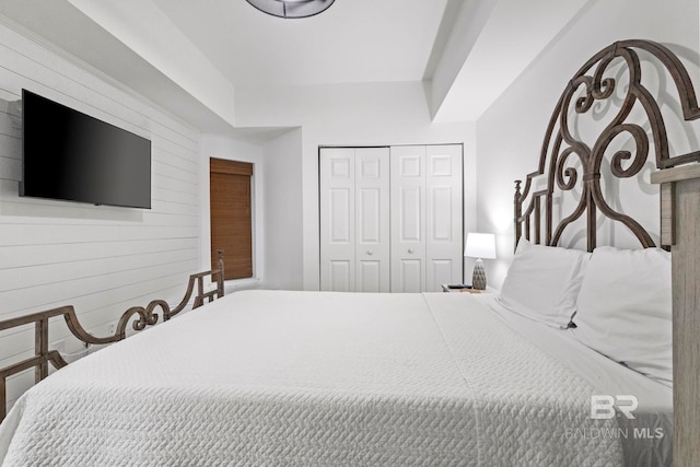 bedroom with a closet and wooden walls