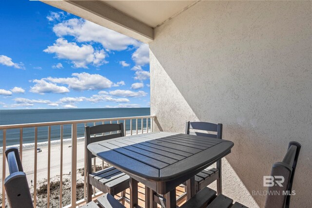 balcony featuring a view of the beach, a water view, and outdoor dining space