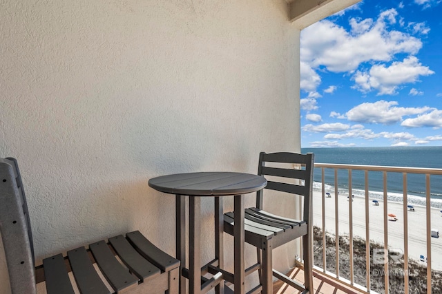 balcony with a water view and a view of the beach