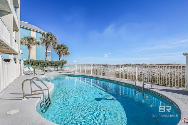 community pool with a patio and fence