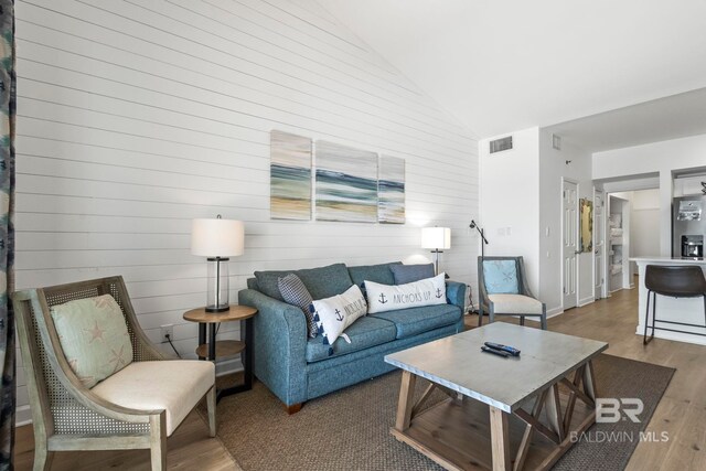 living room with high vaulted ceiling, visible vents, and wood finished floors