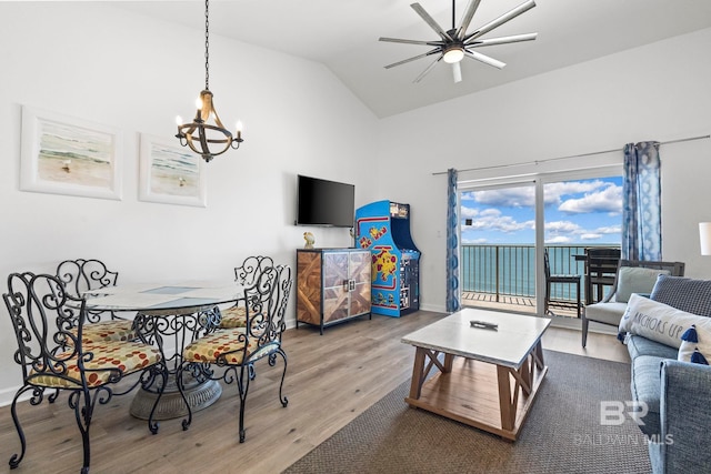 living area with a notable chandelier, baseboards, vaulted ceiling, and wood finished floors