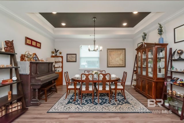 dining area featuring a tray ceiling, wood finished floors, a chandelier, ornamental molding, and baseboards