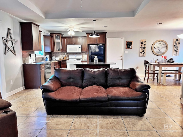 living room featuring ceiling fan, a raised ceiling, and light tile patterned floors