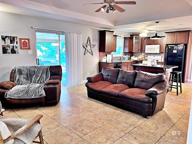 tiled living room with sink, a tray ceiling, and ceiling fan