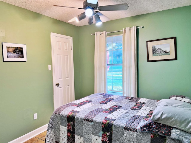 bedroom featuring light tile patterned flooring, ceiling fan, and a textured ceiling