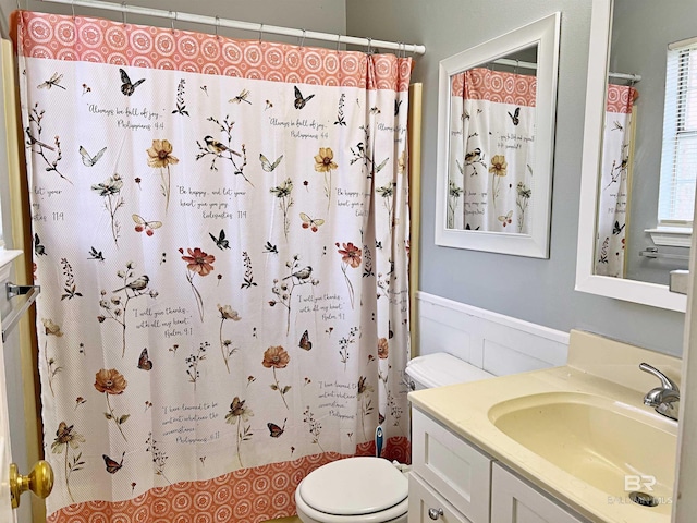 full bath with toilet, vanity, a wainscoted wall, and a shower with curtain