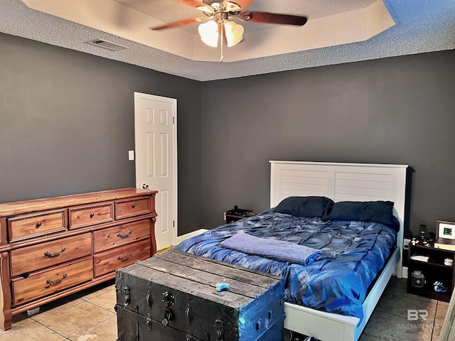 tiled bedroom with ceiling fan and a textured ceiling