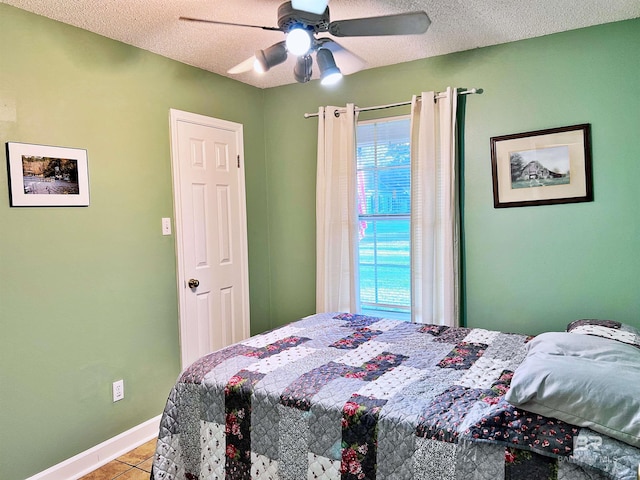 tiled bedroom featuring a textured ceiling, baseboards, and ceiling fan