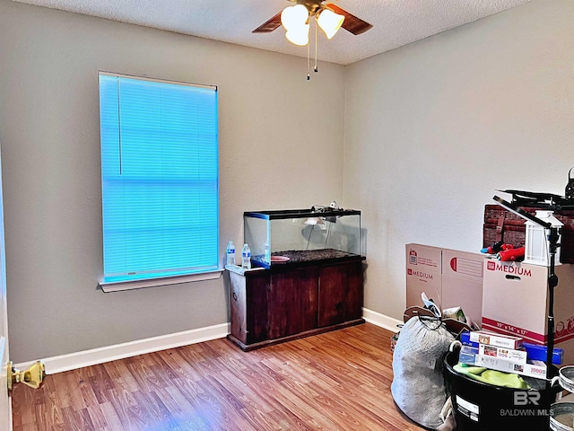misc room featuring ceiling fan, wood finished floors, baseboards, and a textured ceiling