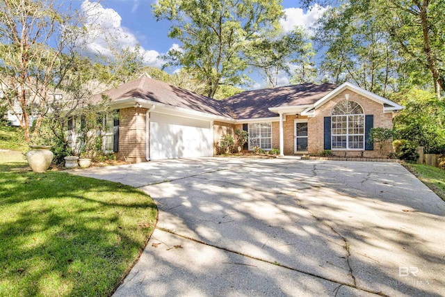 single story home with a garage, a front yard, brick siding, and driveway