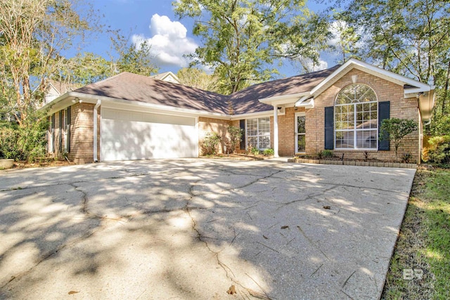 single story home featuring a garage, brick siding, and driveway