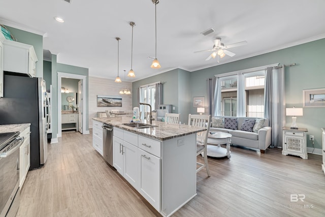 kitchen with an island with sink, white cabinetry, stainless steel appliances, and a sink