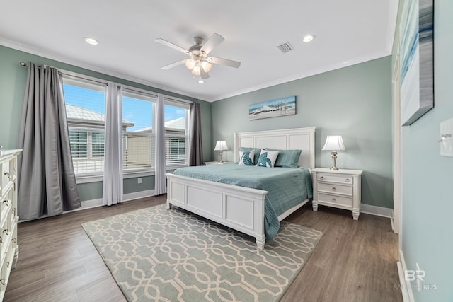 bedroom with dark wood-style floors, recessed lighting, crown molding, and baseboards