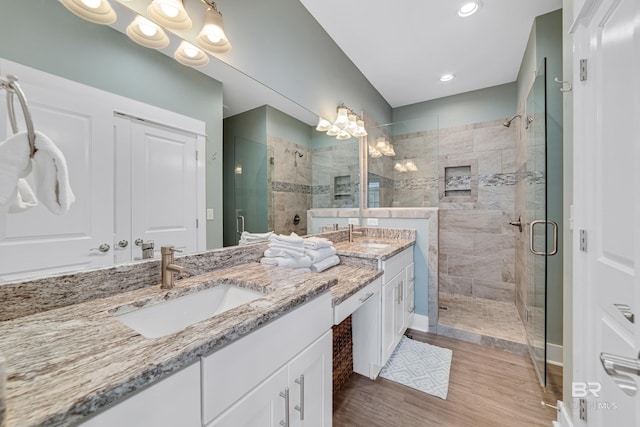 full bathroom with a shower stall, a sink, and wood finished floors