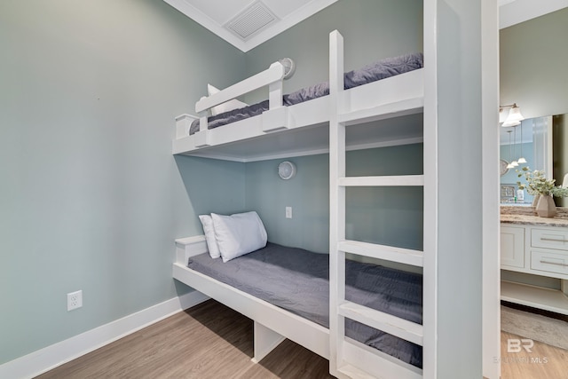 bedroom featuring baseboards, visible vents, crown molding, and light wood finished floors