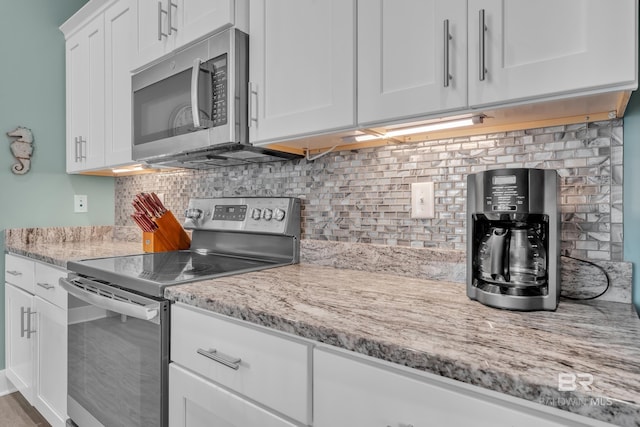 kitchen with stainless steel appliances, white cabinetry, tasteful backsplash, and light stone countertops