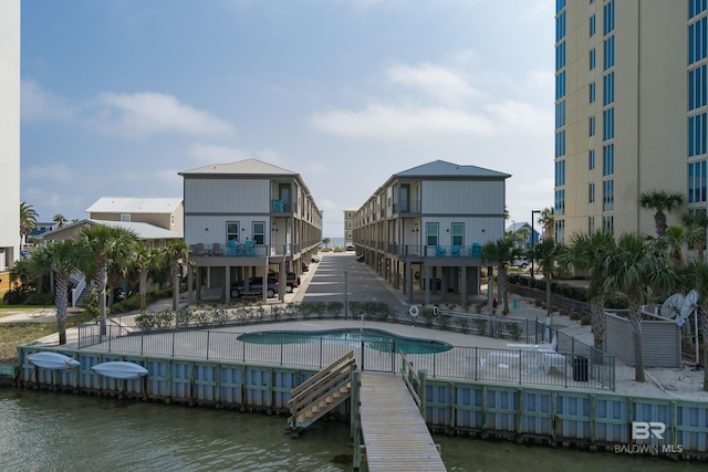 back of property featuring a patio, a water view, fence, and a community pool