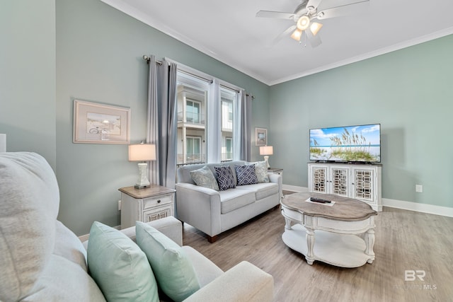 living room with light wood-style floors, crown molding, baseboards, and ceiling fan