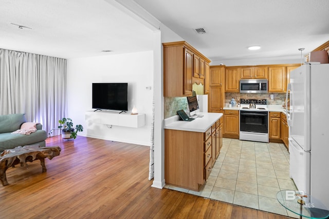 30577 Baldwin St, Perdido Beach, AL 36530 - kitchen featuring white appliances, open floor plan, light countertops, tasteful backsplash, and light wood-style flooring