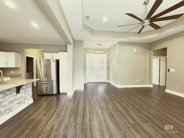 unfurnished living room featuring dark wood-style floors, a raised ceiling, and ceiling fan