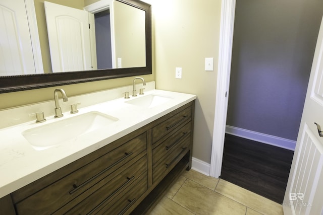 bathroom featuring a sink, baseboards, double vanity, and tile patterned floors